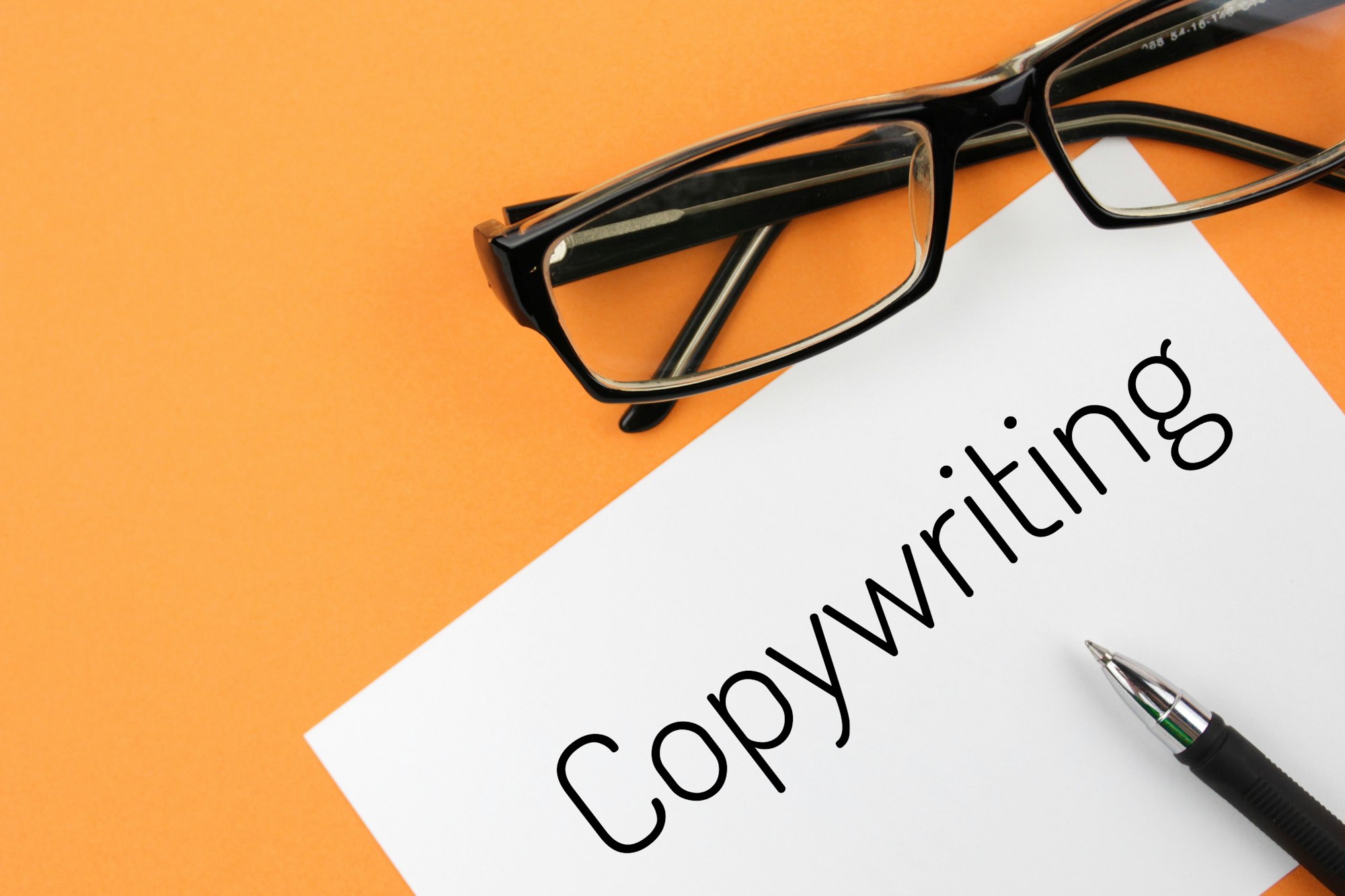 Reading glasses and blank with word copywriting on a orange background